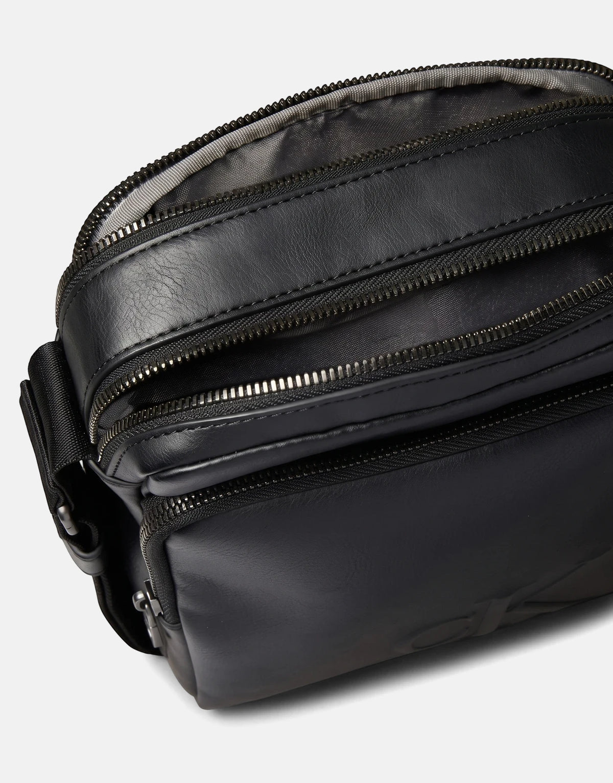 Close-up view of a black Calvin Klein Bold CK Pocket Reporter Bag, featuring multiple zippered compartments and a textured