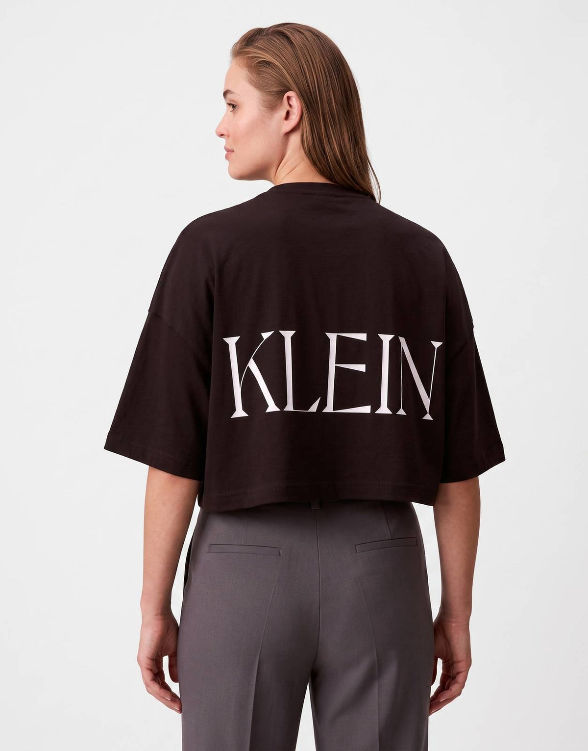 Calvin Klein Cropped Graphic T-Shirt in black, featuring a white 'KLEIN' logo prominently displayed on the back.