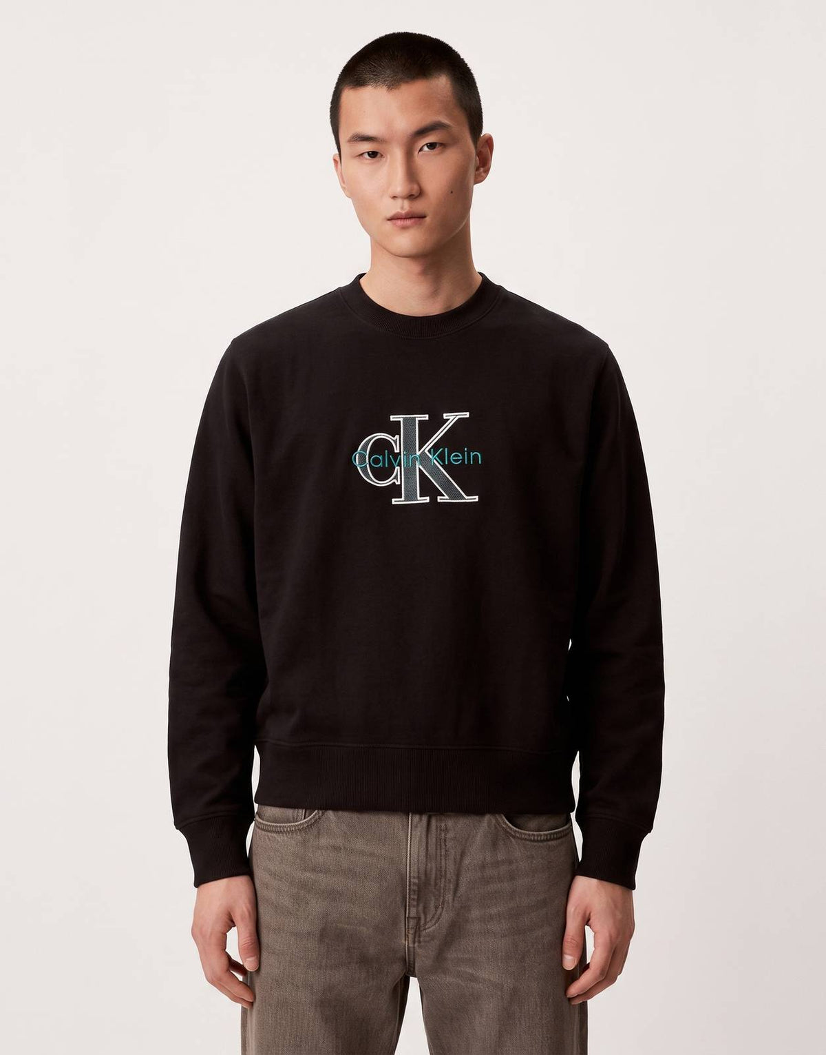 Calvin Klein Premium Tri-Color Monologo Black Sweatshirt on a male model, showcasing the front with hands in pockets.