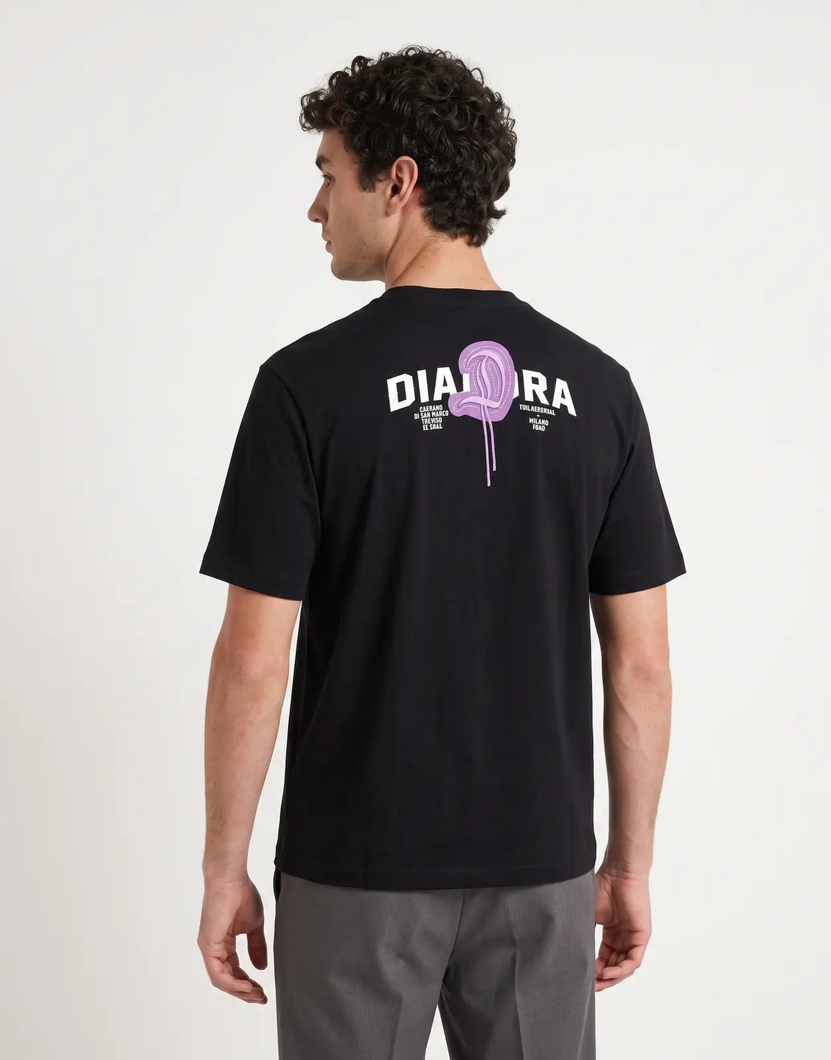 Diadora Vado Black T-Shirt, featuring a purple heart logo and text print on the back, modeled in a studio.