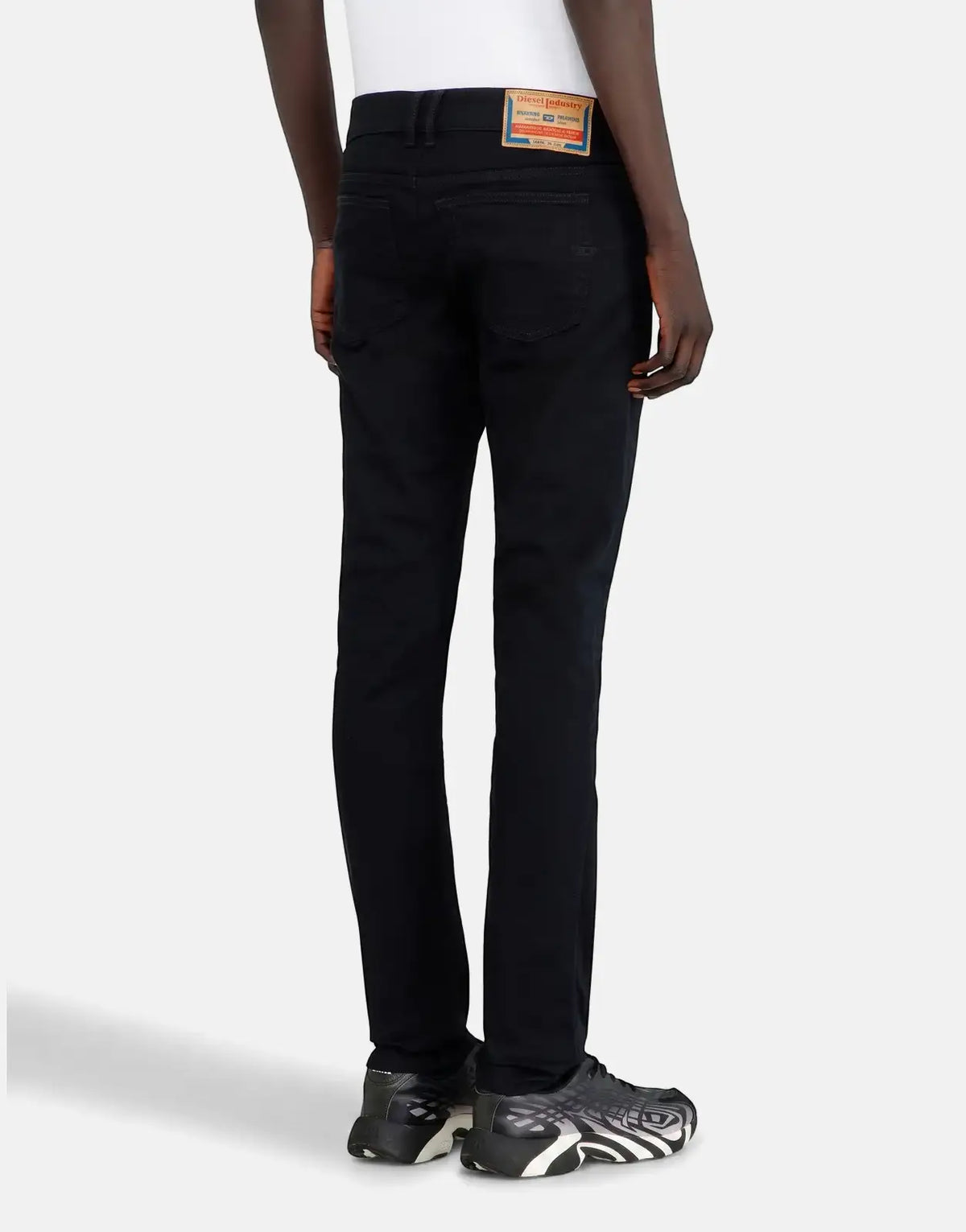 Rear view of men's Diesel 1979 Sleenker 02 skinny jeans in black denim, featuring the brand's iconic back label.