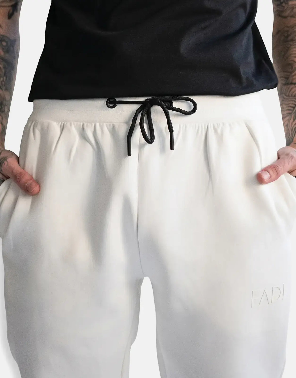 Off-white Fade Essential Sweatpants with black drawstring, embossed logo, and pockets, worn by a model from the waist up.