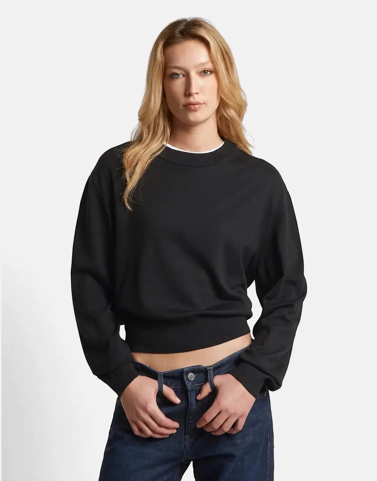 Blonde woman wearing a G-Star RAW Boxy Knit Dk Black sweater and dark blue jeans in a studio setting.