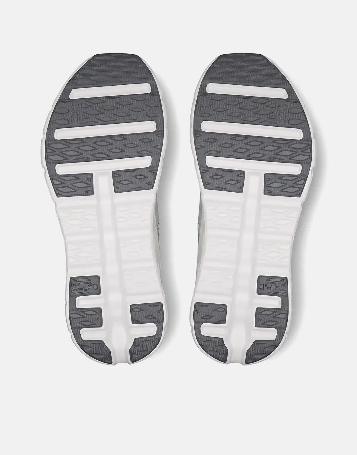 Soles of two On Men's Cloudtilt Tide Mineral sneakers in white with dark gray tread, viewed from below.