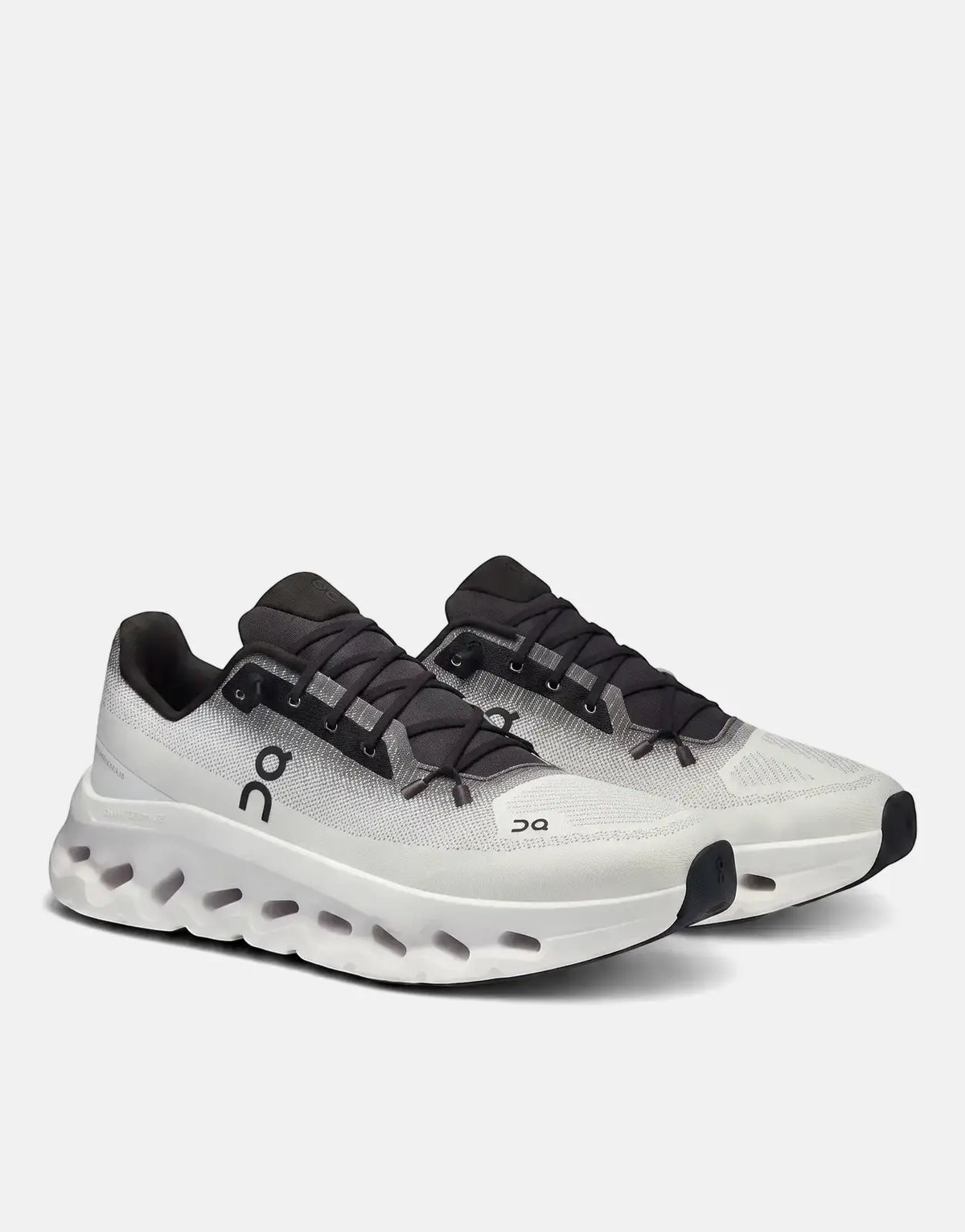 Pair of On Unisex Cloudtilt Black Ivory Sneakers on a white background, showing the side profile and textured sole.