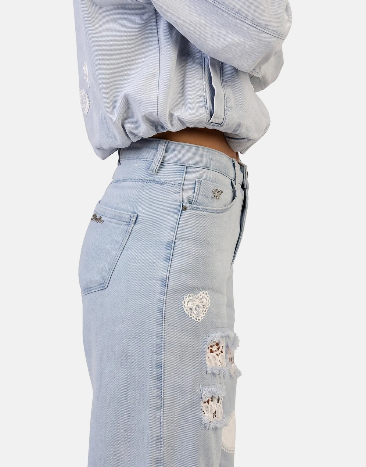Close-up of Sissy Boy Kiera wide leg light vintage jeans featuring distressed details with white lace and heart-shaped