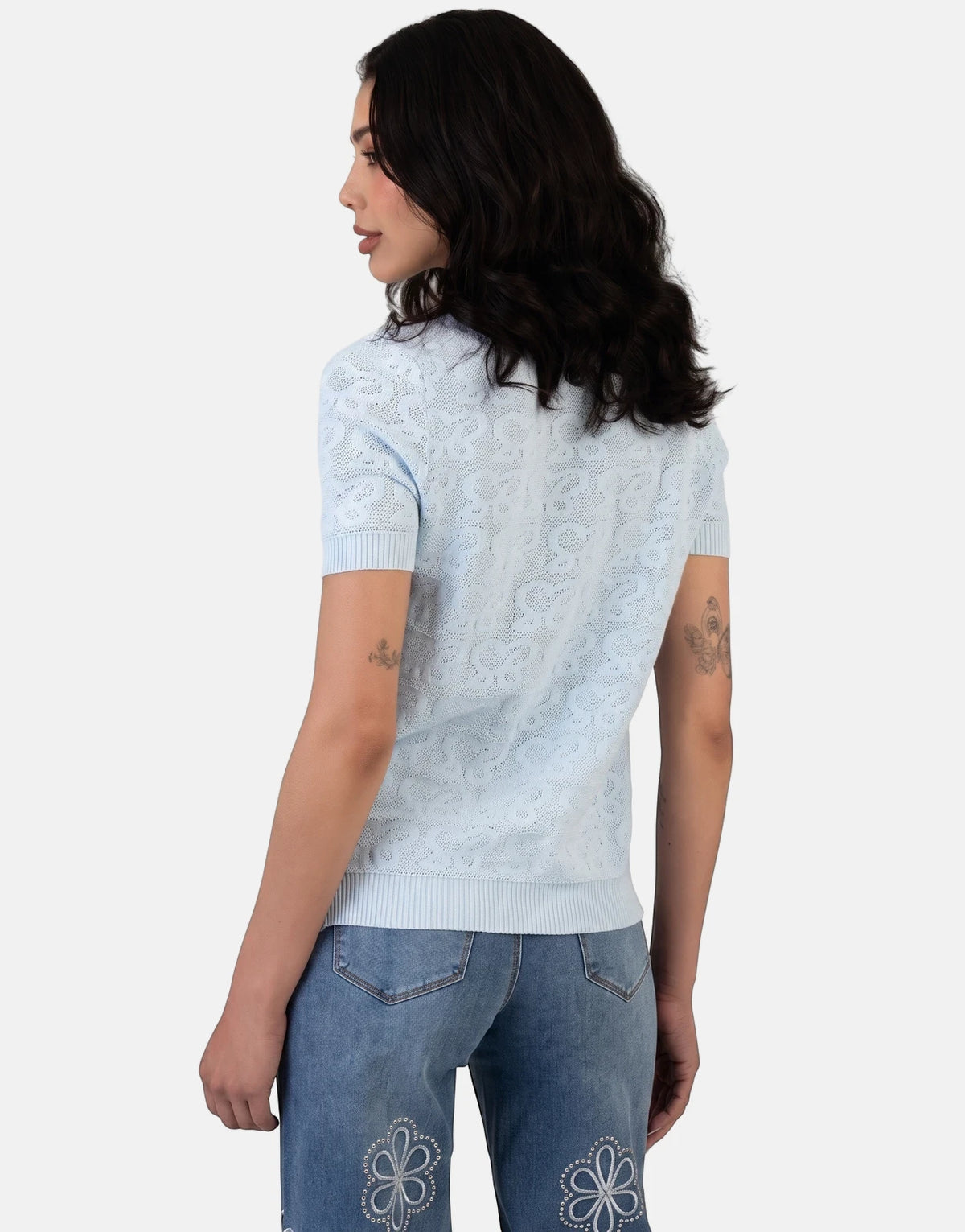 Female model wearing Sissy Boy Next Level Pale Blue Knit Top with knit pattern and short sleeves, paired with embroidered