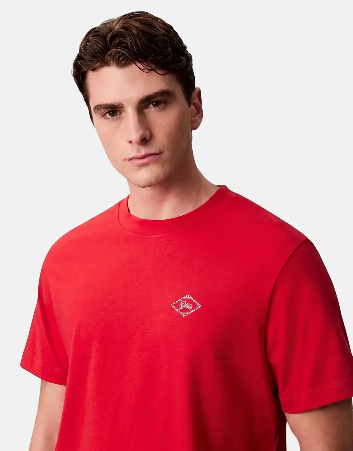 Male model wearing a Calvin Klein 20s Matchbox Graphic Red T-shirt, featuring a white diamond logo on the chest, in a studio