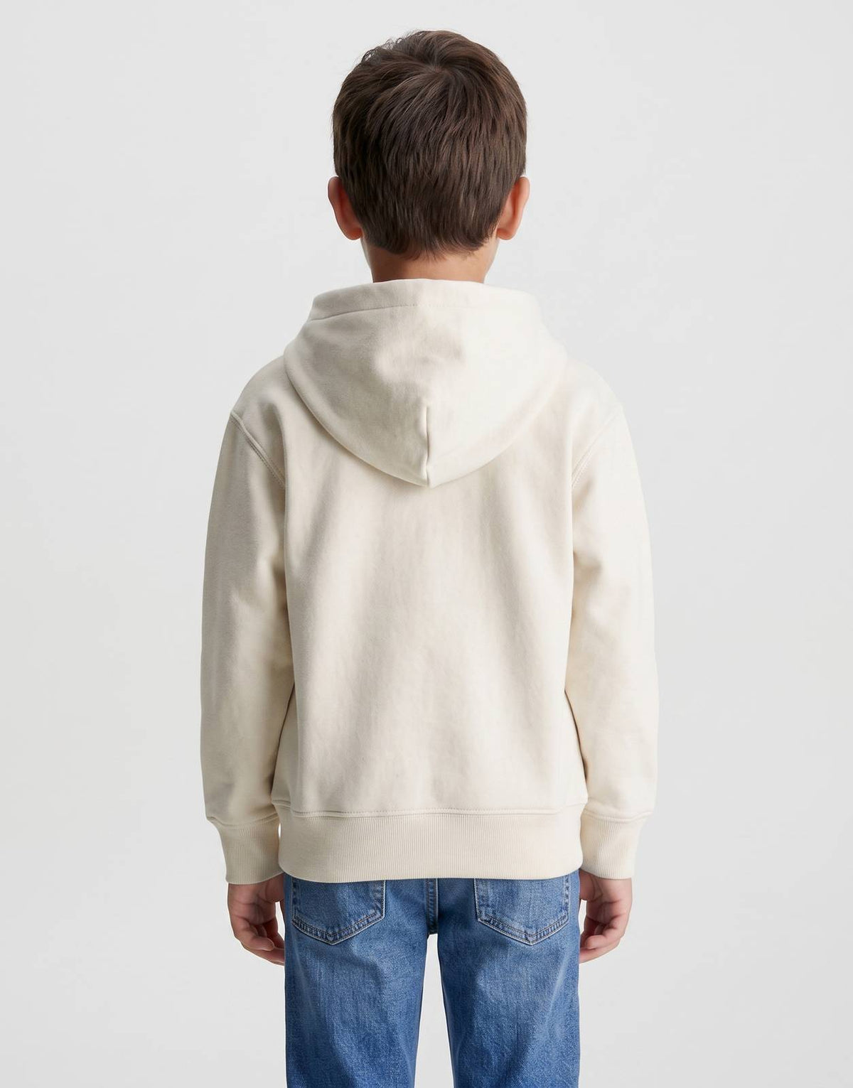 Back view of a Calvin Klein Kids Color Logo Hoodie in cream, worn by a child model, paired with blue jeans.