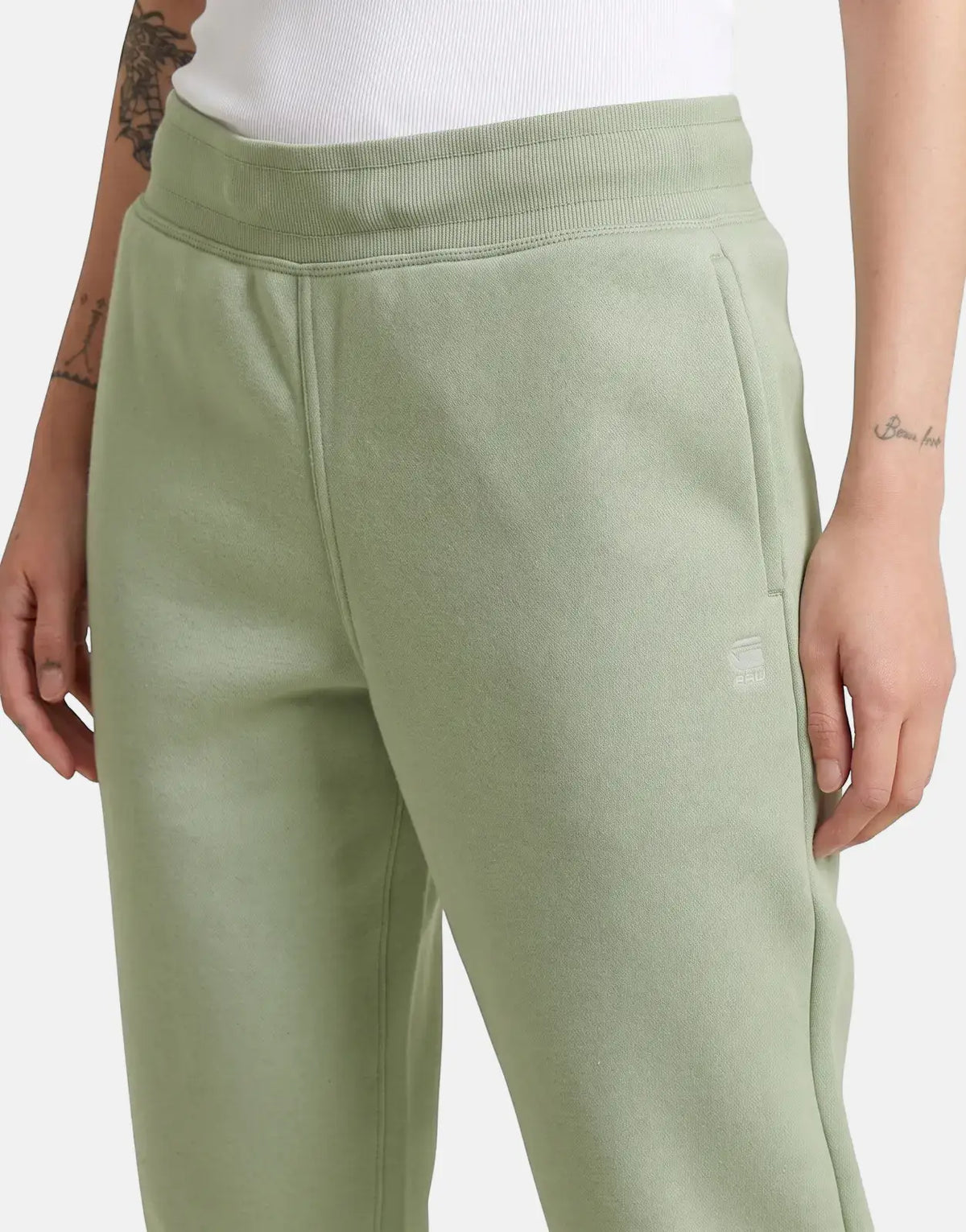 Close-up of G-Star RAW Premium Core 2.0 pale green sweatpants on a model, showcasing the ribbed waistband and soft fabric.