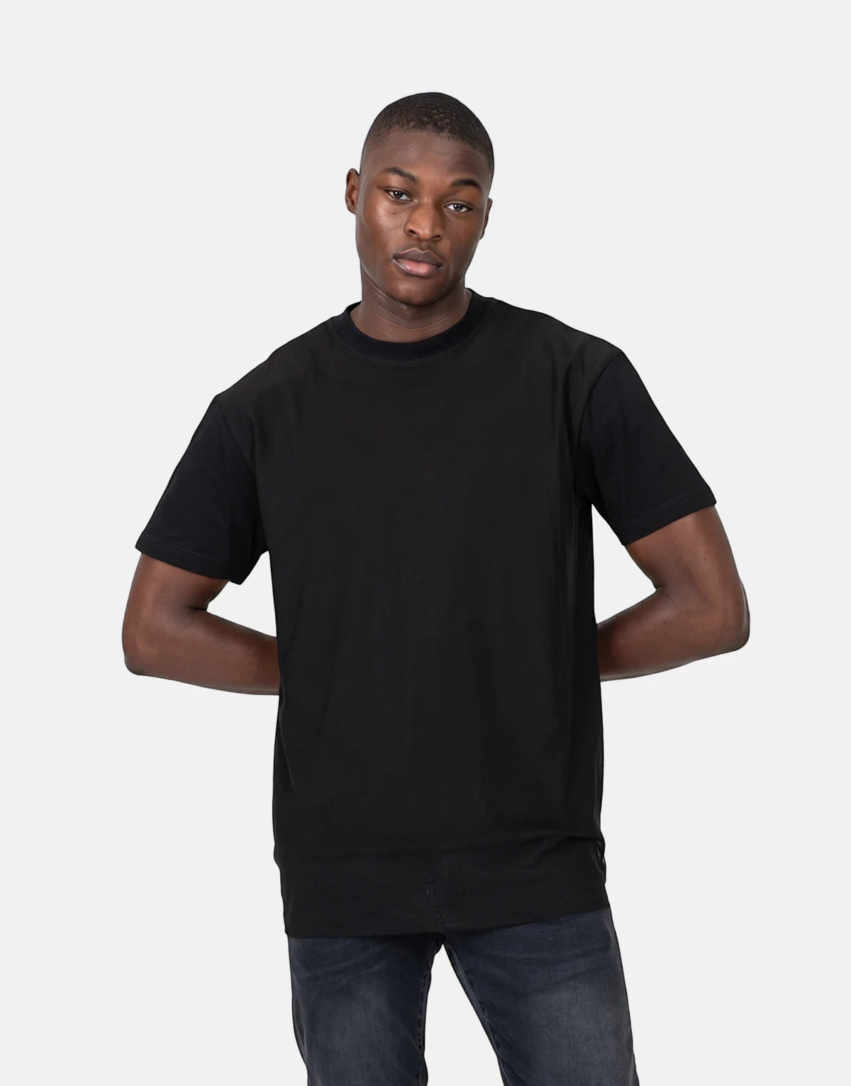 A male model showcases the Les Hommes Tulle Black T-Shirt, a classic short-sleeve crew neck, paired with dark jeans.