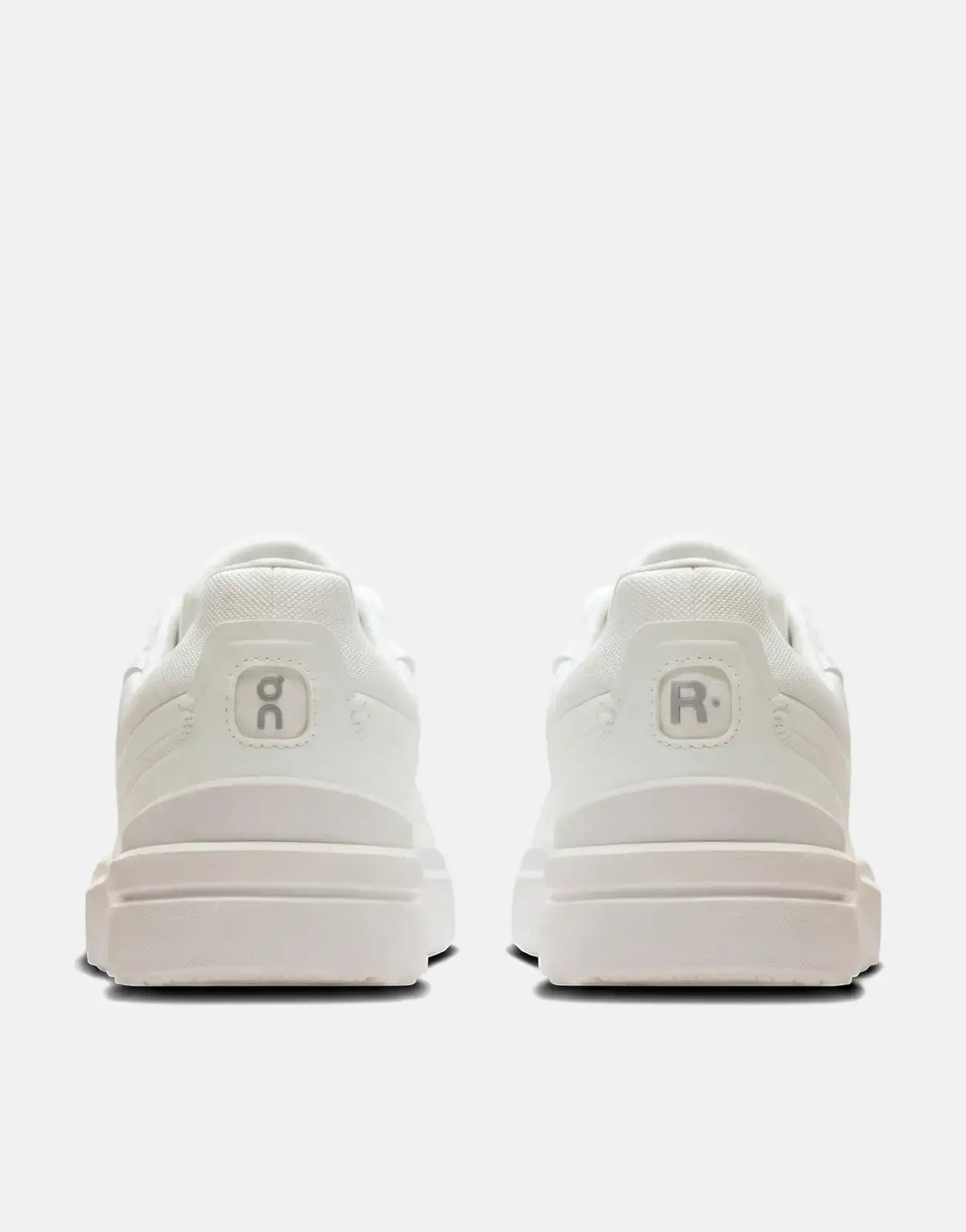 Rear view of two On Men's Roger Advantage white sneakers, showing the heel designs with the On logo and R logo.