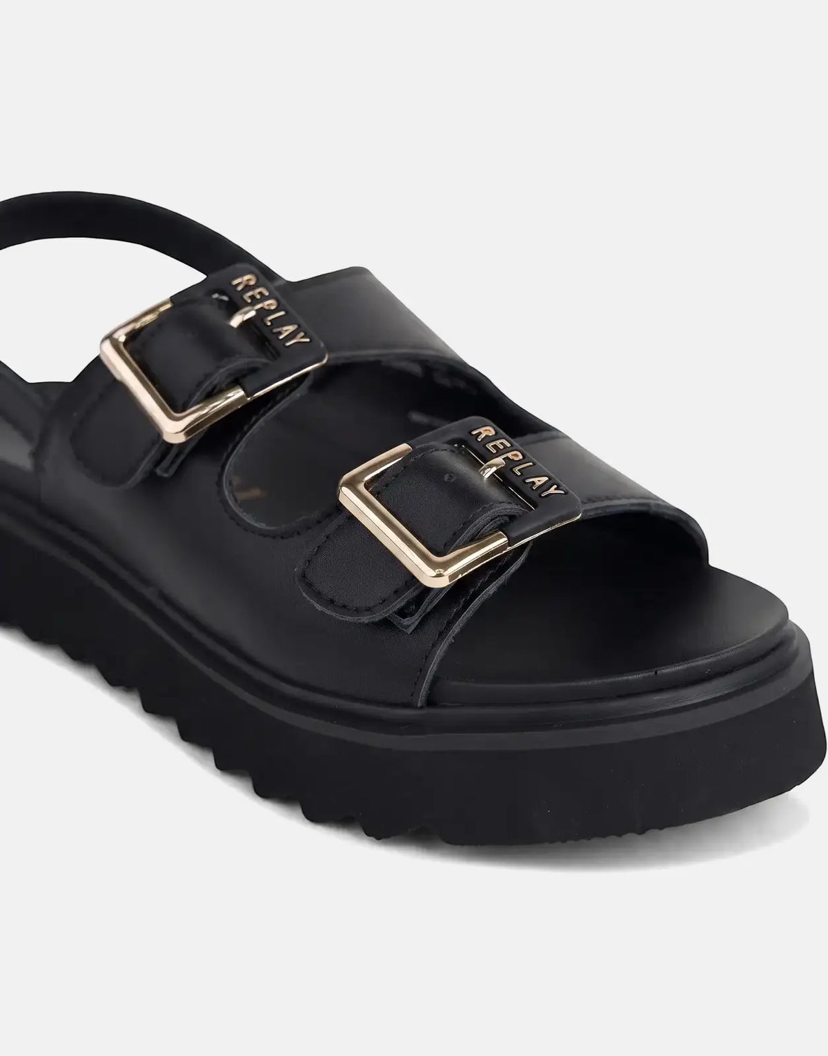 Close-up of a black Replay New Alicante Tonal sneaker with gold-tone 'Replay' buckles and a thick, ridged platform sole.