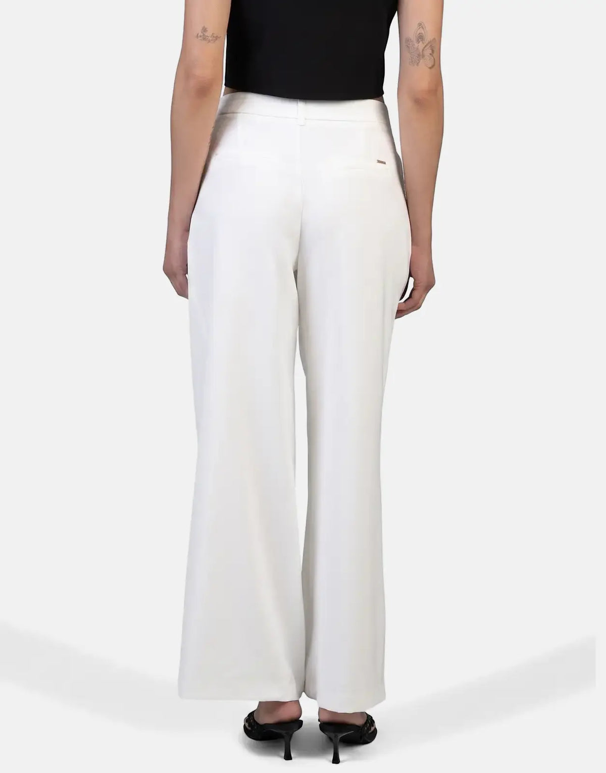 Back view of a model wearing Sissy Boy Alice Wide Leg Off White Trousers and a black top, paired with black heels.