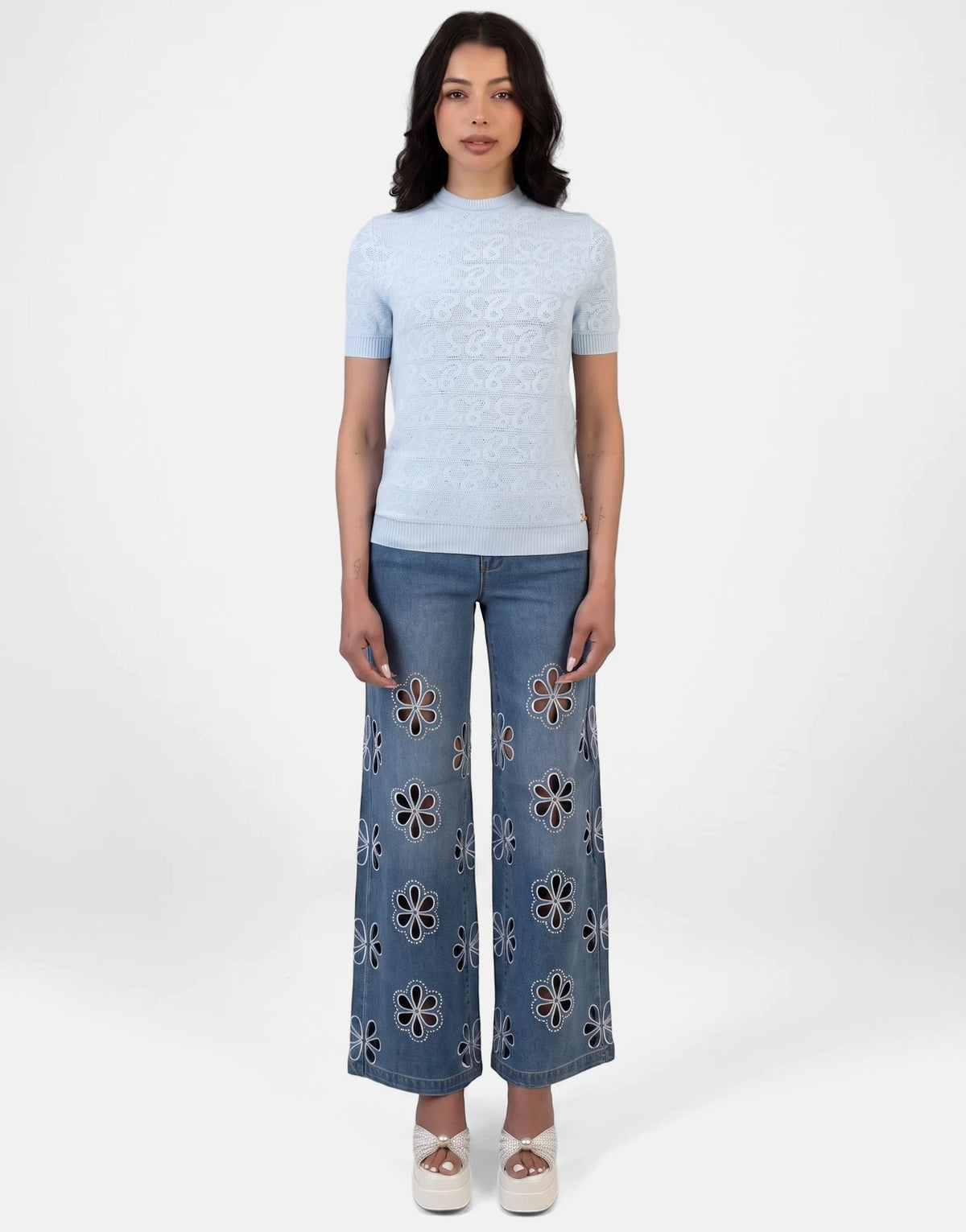 Sissy Boy Next Level pale blue knit short sleeve top, styled with wide-leg floral cut-out jeans and white platform sandals.